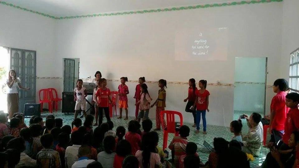 Children performing at the front of the Mission House hall while others watch