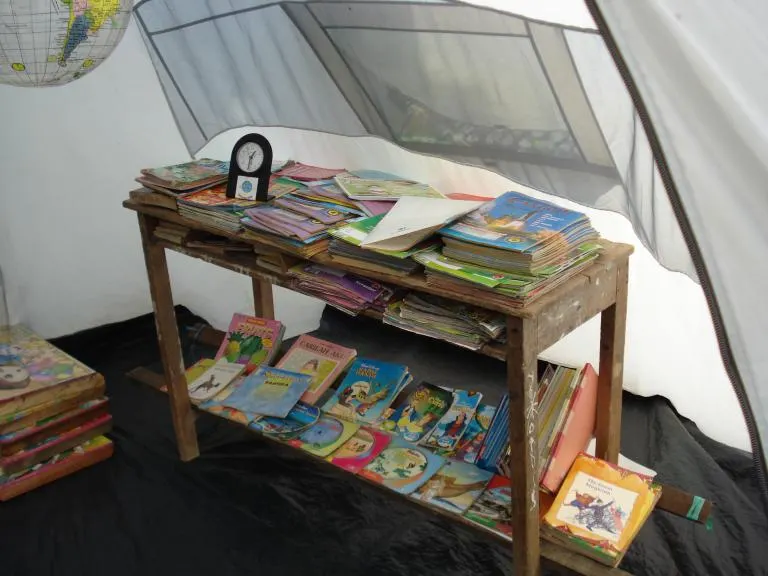 Children's books laid out on a wooden table inside the library tent in Padang